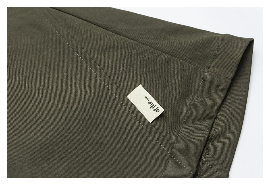 Close-up of an olive trouser hem with a small sewn English-text label.