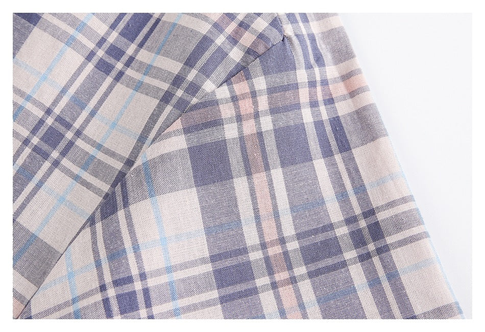 Close-up of the pale plaid shirt's sleeve seam and fabric pattern.