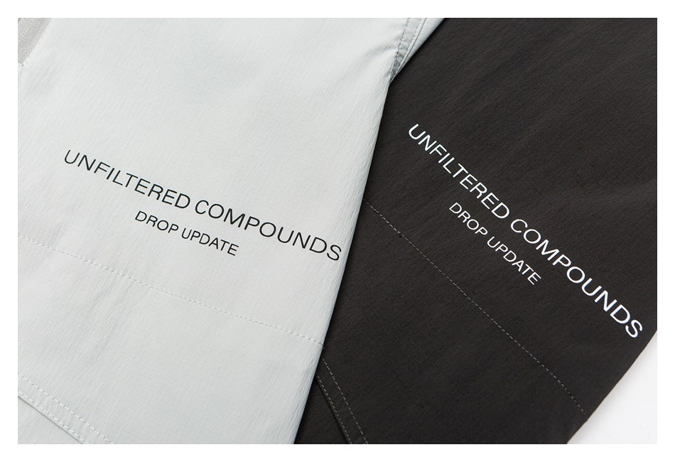 Close-up of pale gray and charcoal garment panels, each printed with “UNFILTERED COMPOUNDS” and “DROP UPDATE.”