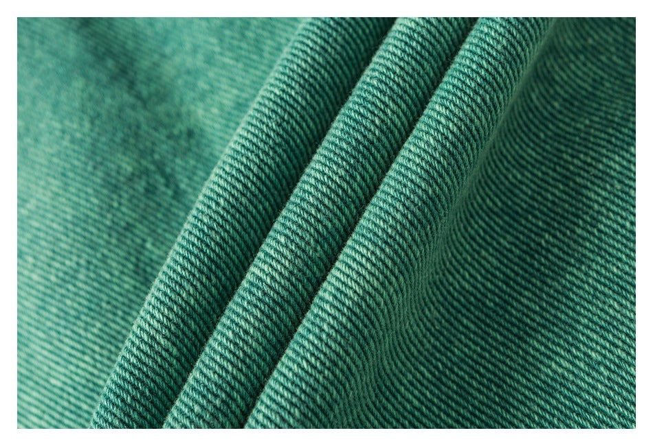 Macro view of teal denim twill texture with several folded ridges.