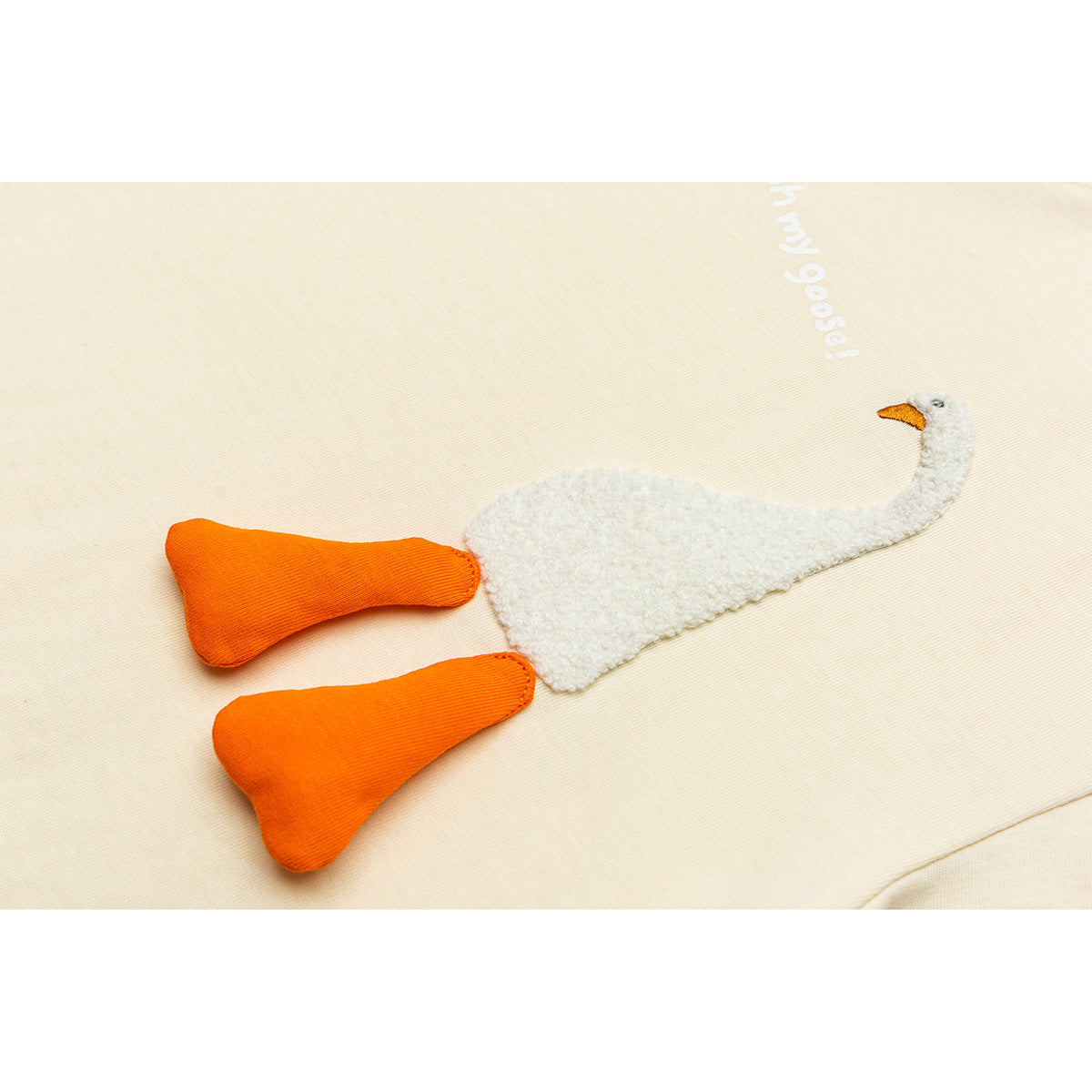 Close-up of an ivory T-shirt with a textured white goose appliqué, orange legs and white lettering.