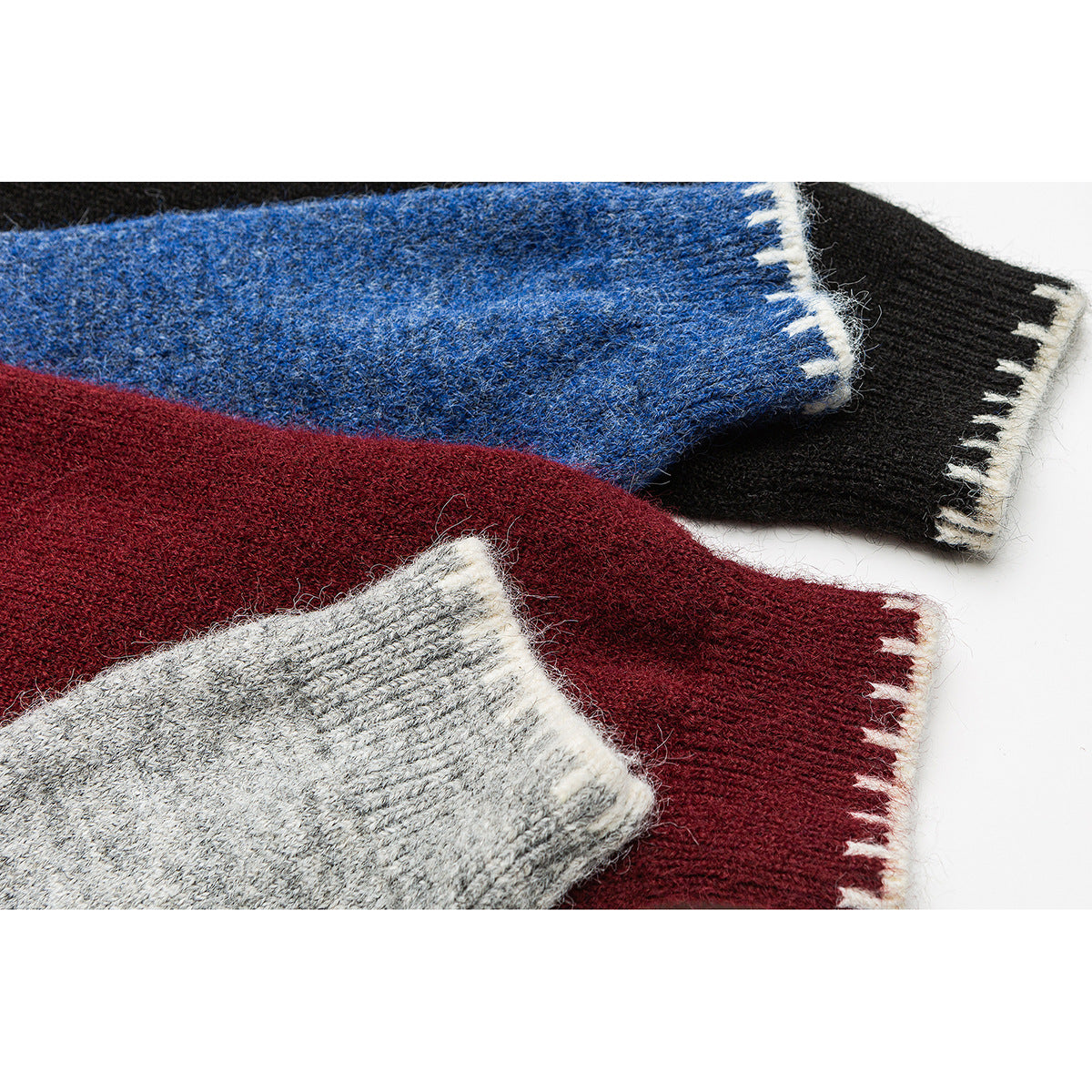 Close-up of overlapping sweater cuffs in blue, black, burgundy, and gray, with contrasting trim.