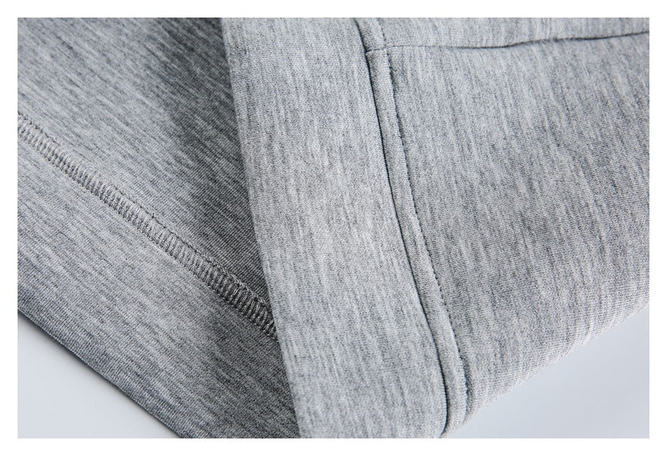 Close-up of heather gray garment construction with an overlocked seam and folded fabric edge.