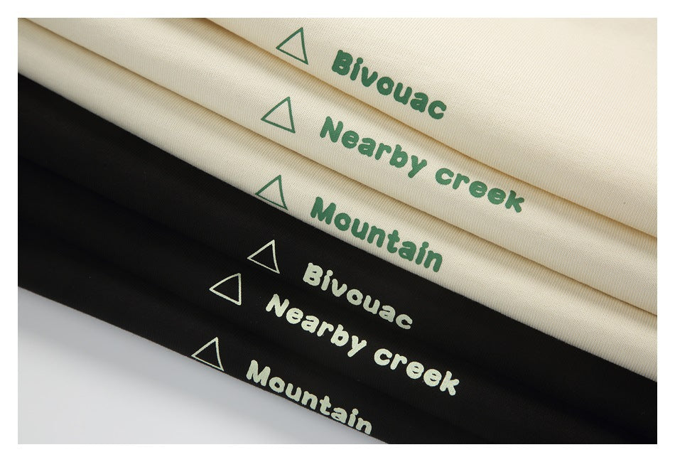 Folded cream and black fabric swatches printed with green or pale mountain icons and English words.