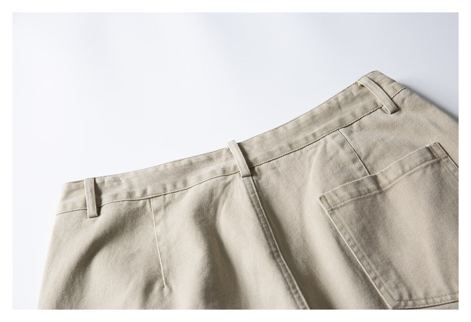 Close-up of beige trousers showing the waistband, belt loops, seam, and part of a rear pocket.