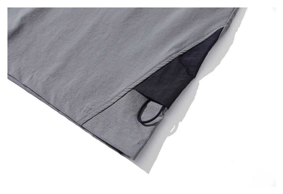 Close-up of a gray top’s side hem with a dark insert and loop detail.