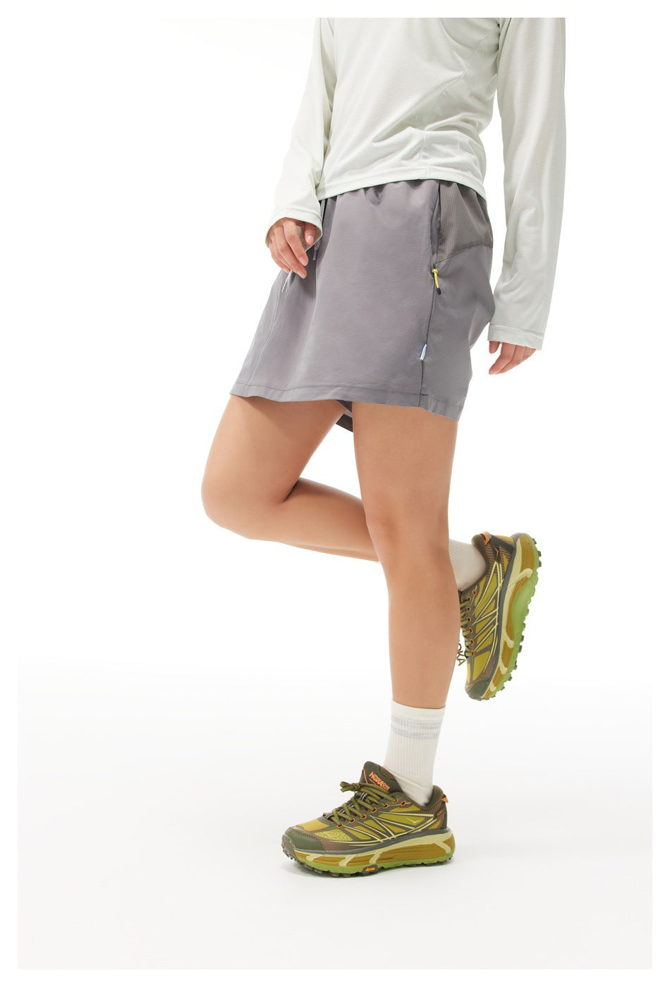 Angled side view of a model wearing a gray athletic skirt with a small zip pocket.