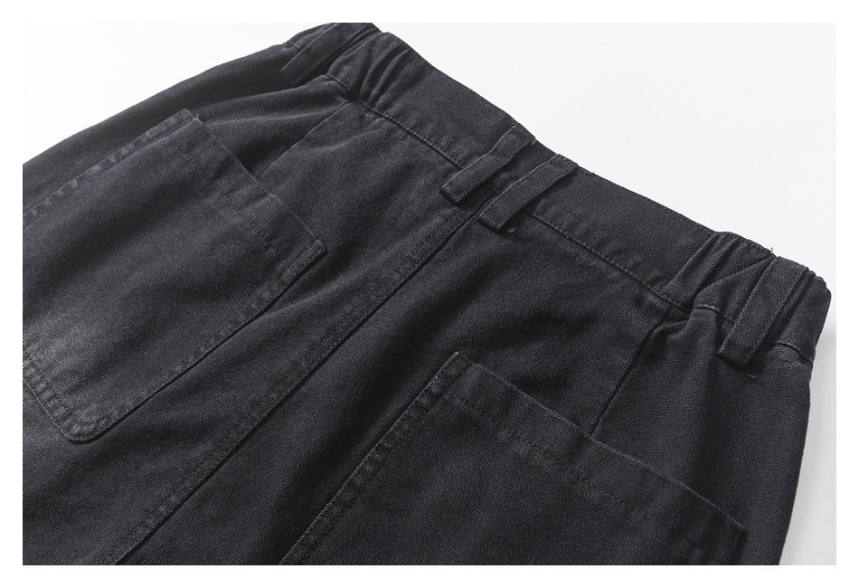 Close-up of the back of black trousers, showing the waistband, belt loops, and two patch pockets.