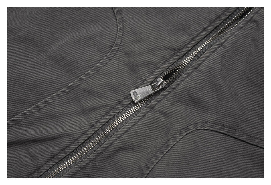Close-up of a silver zipper and stitching on charcoal jacket fabric.