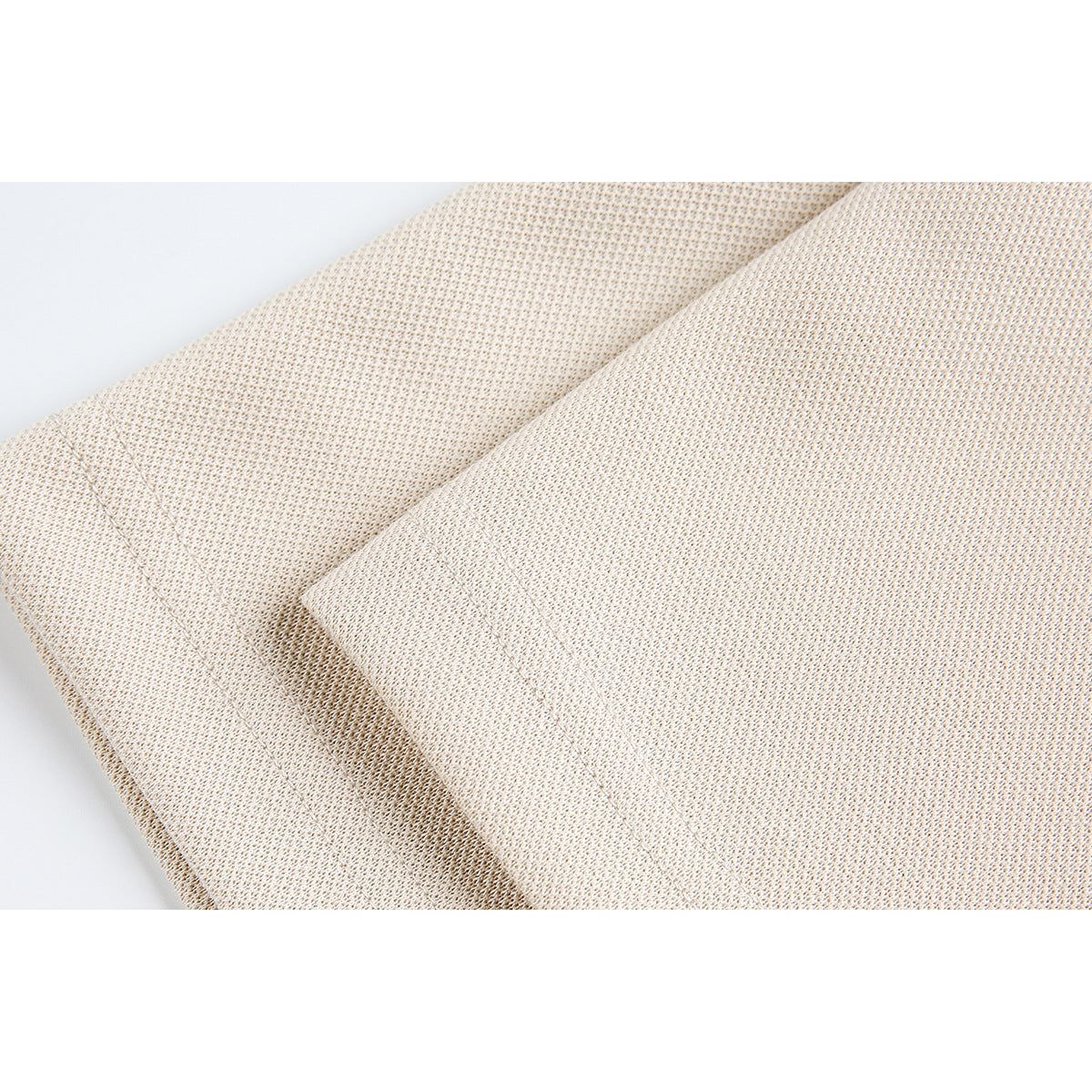 Close-up of overlapping cream knit fabric panels and a stitched seam.