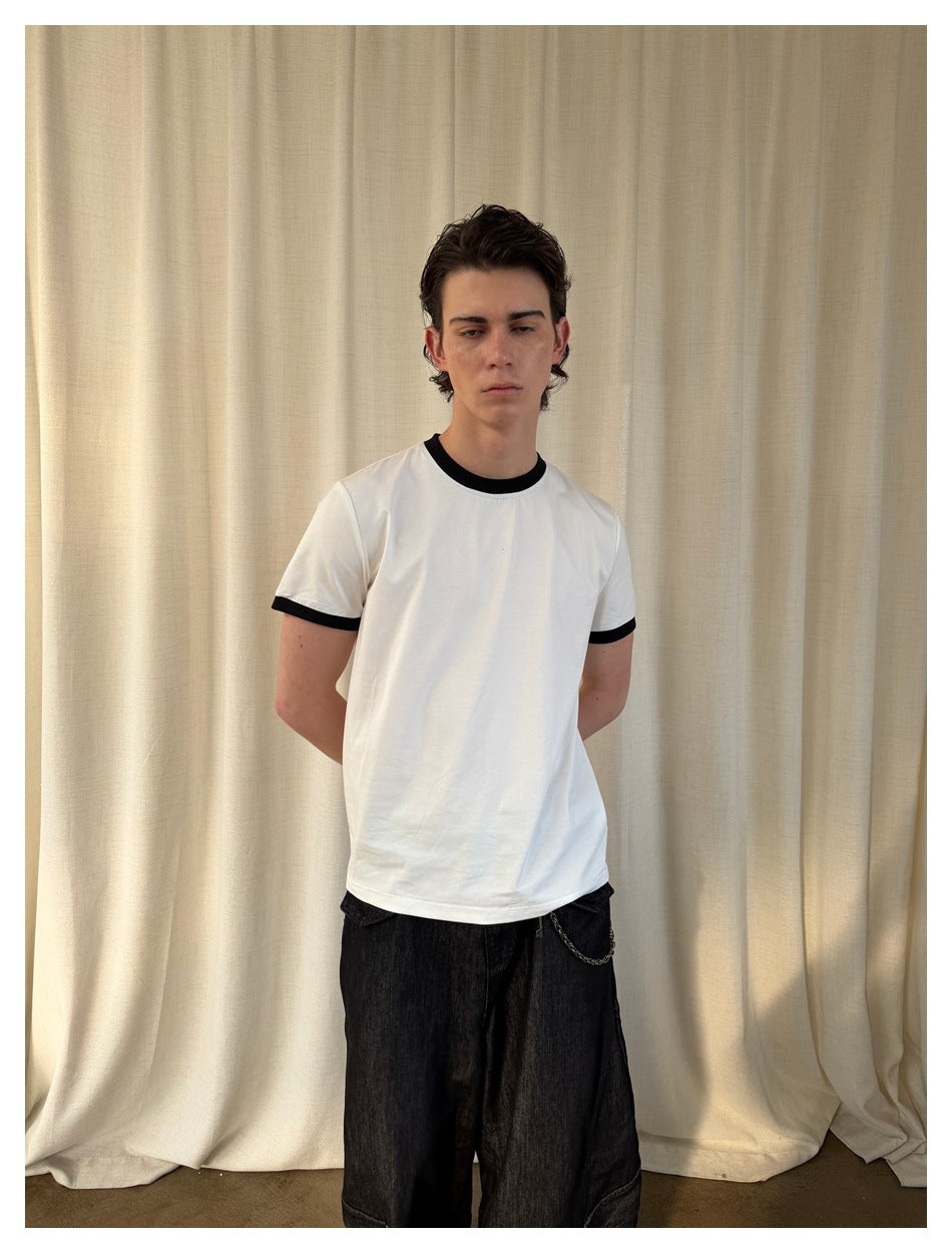 Closer front view of a model wearing a plain white T-shirt with black neck and sleeve trim.