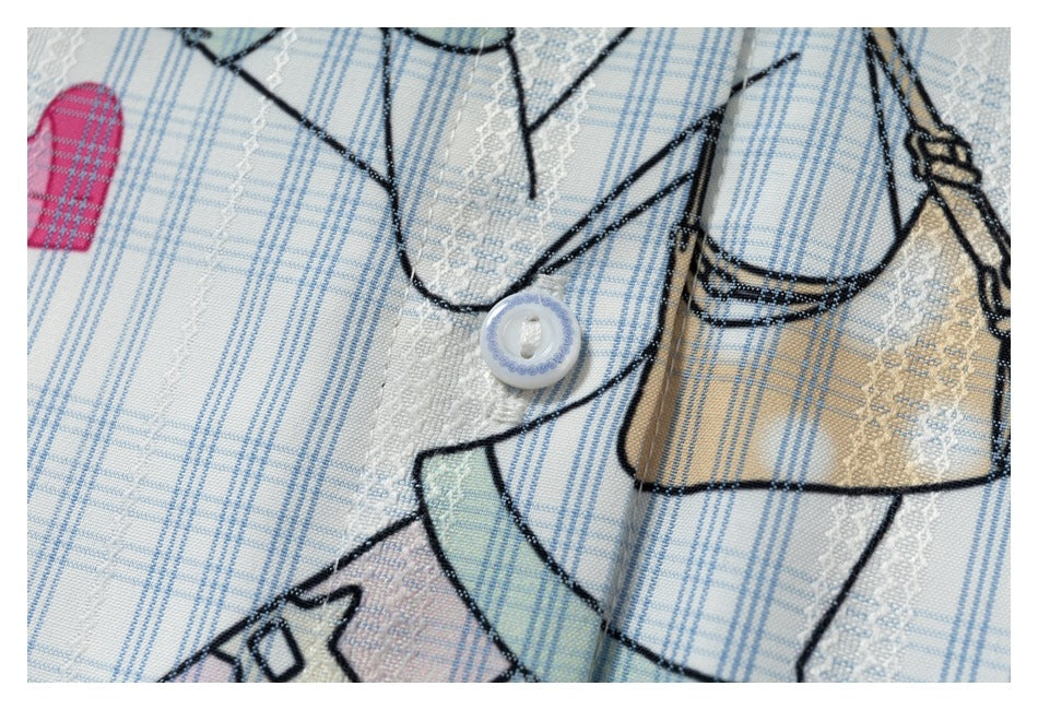 Close-up of a white button and cartoon print on a white shirt with blue plaid and textured stripe details.