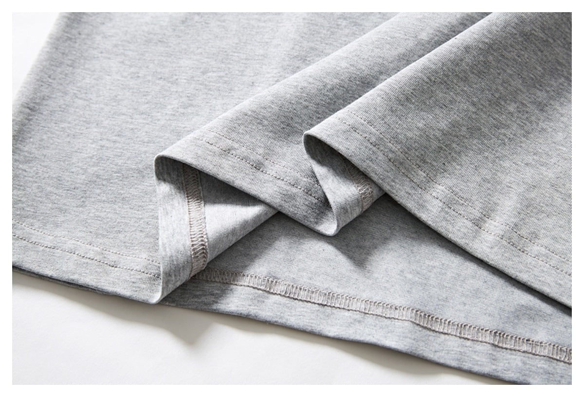 Close-up of a light gray heather knit garment with folded hems and visible overlock stitching.