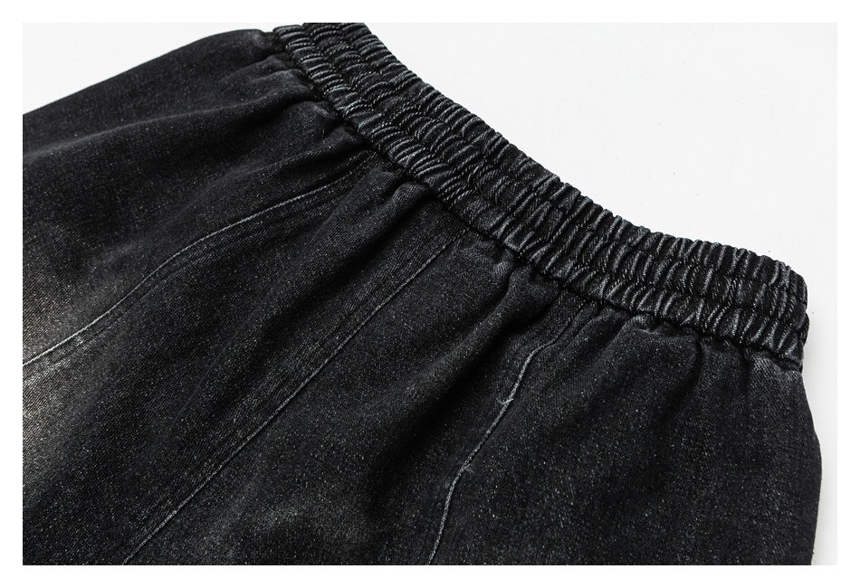 Close-up of black pants showing a gathered elastic waistband and stitched seams.