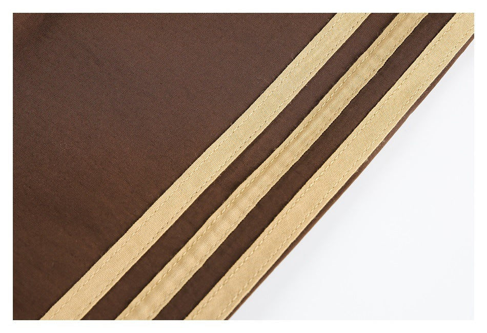 Close-up of three tan stripes stitched along the side of brown track pants.