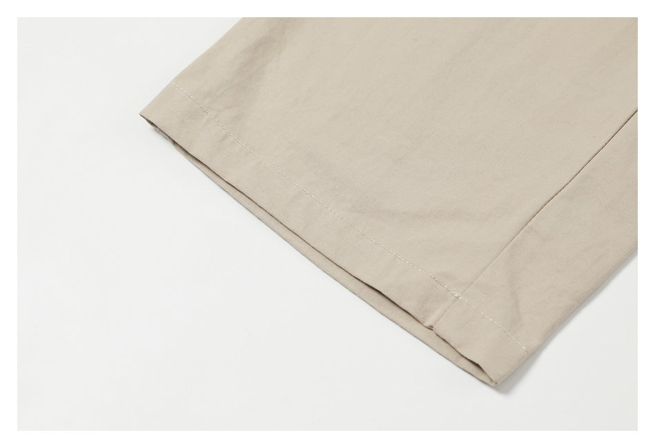 Close-up of the stitched hem on beige trouser legs.