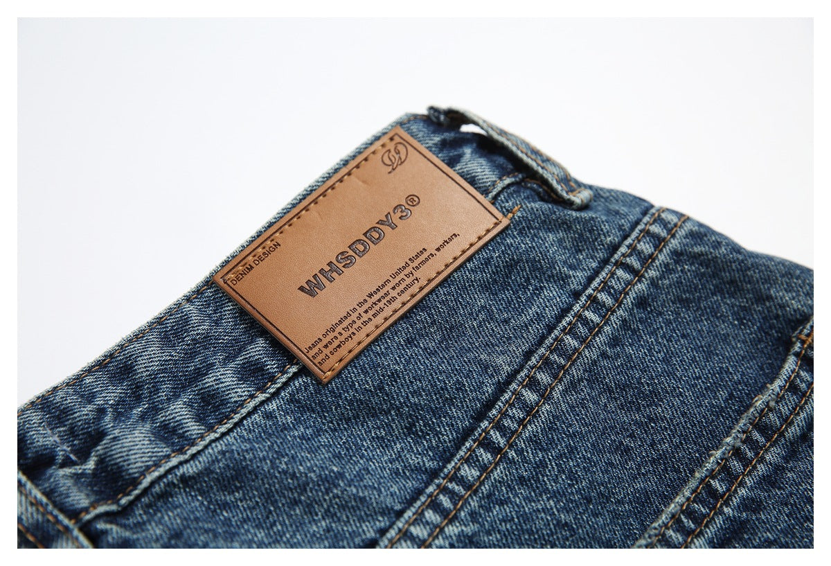Close-up of a tan branded leather patch on the waistband of blue jeans.