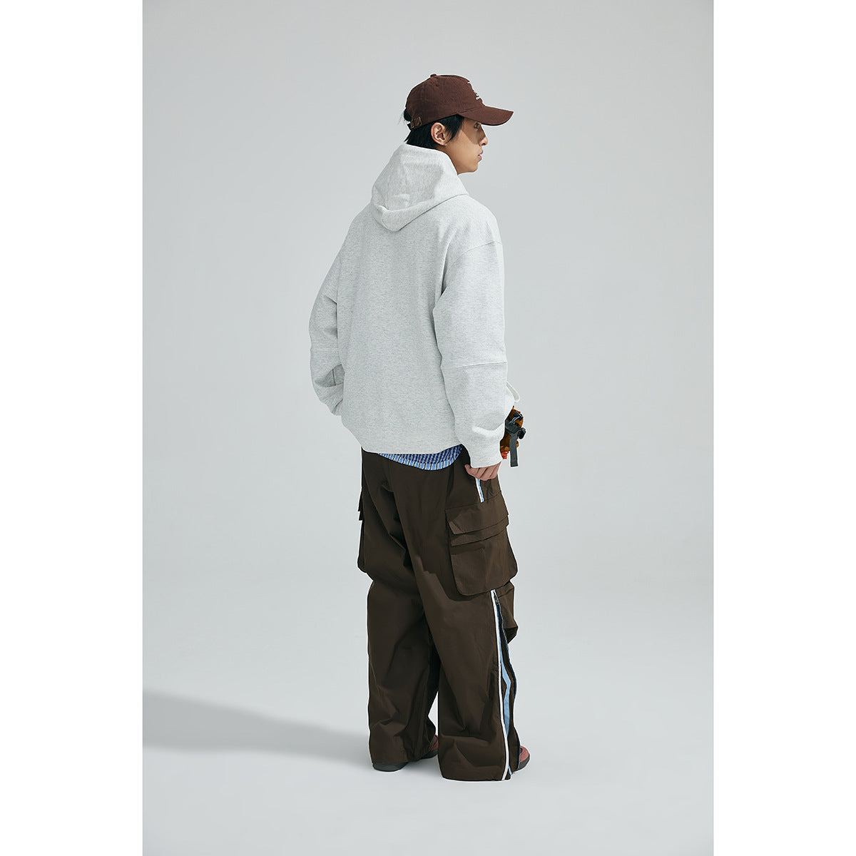Model wearing the light gray hooded sweatshirt, shown from behind with the hood up.