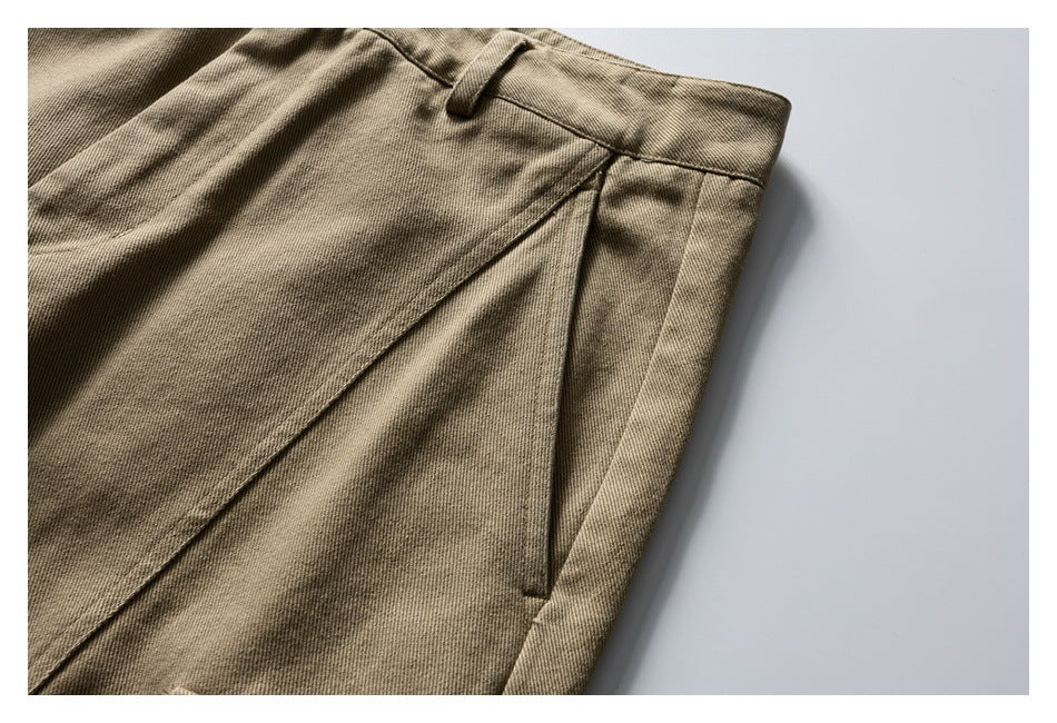 Close-up of tan trousers showing the waistband, belt loop, and slanted front pocket.