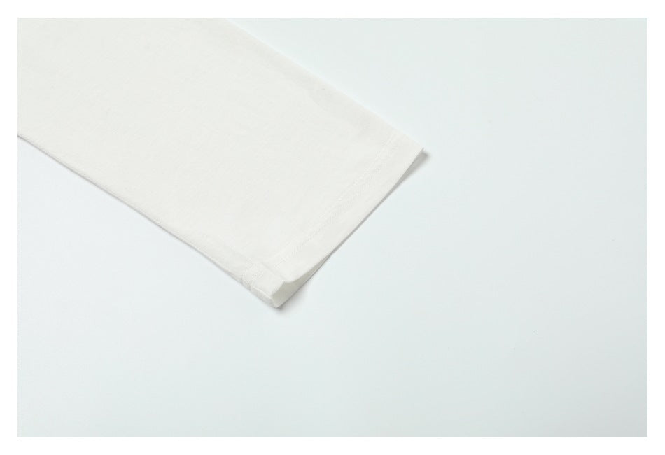 Close-up of a white garment sleeve hem with visible stitching against a pale background.