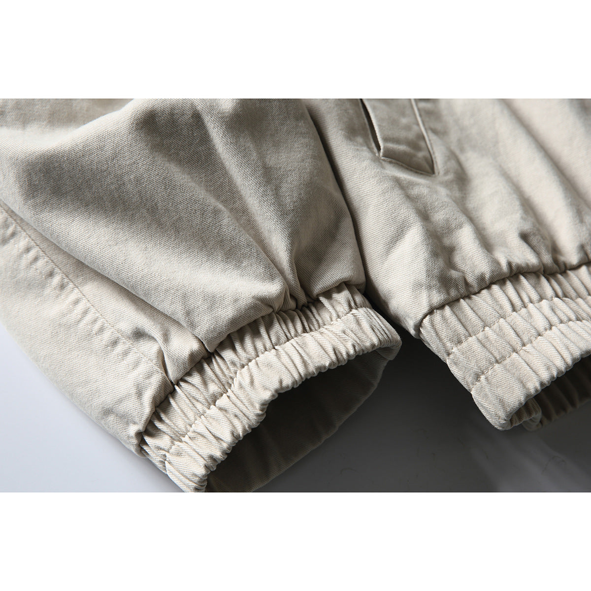 Close-up of an off-white jacket sleeve with a gathered elastic cuff and seam details.