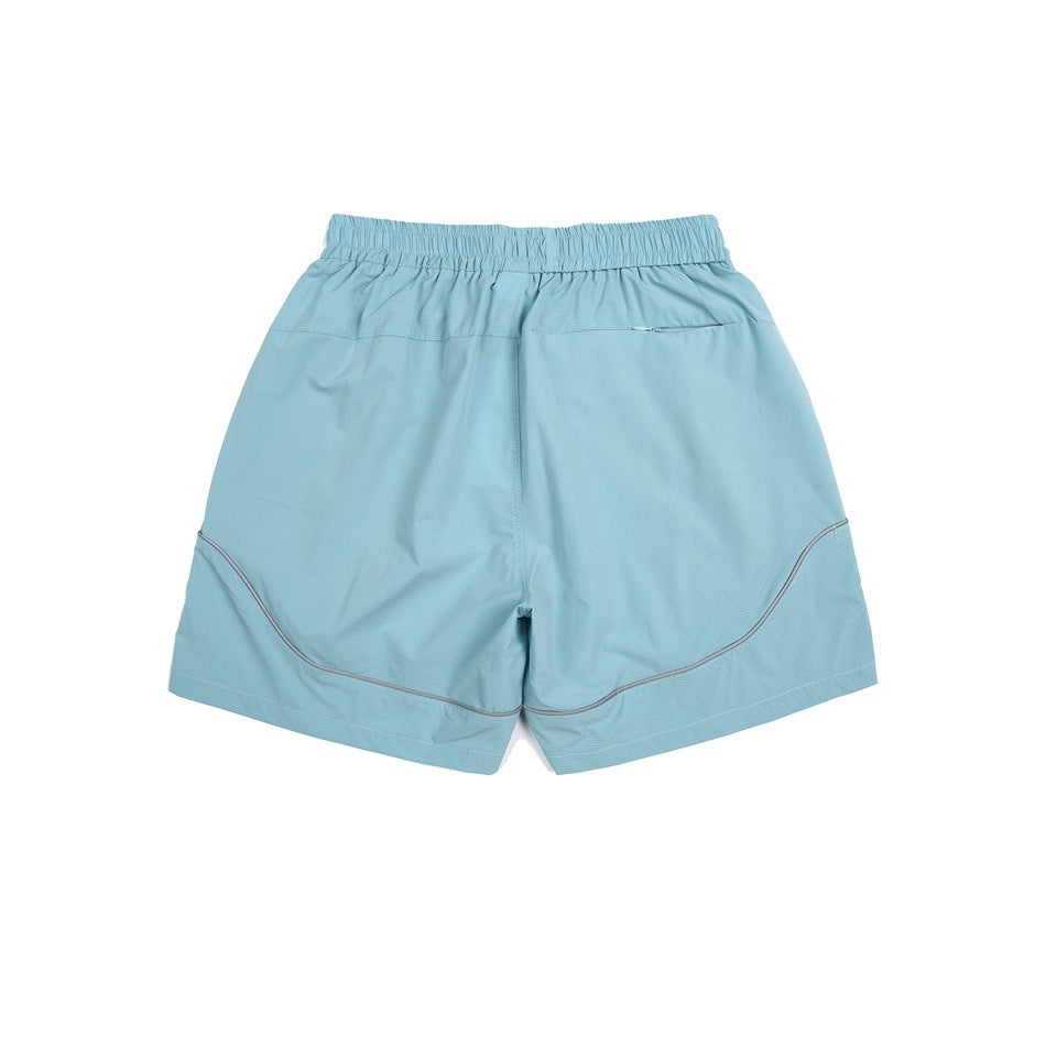 Pale aqua athletic shorts, back view, with an elastic waistband, small zip pocket, and curved piping.