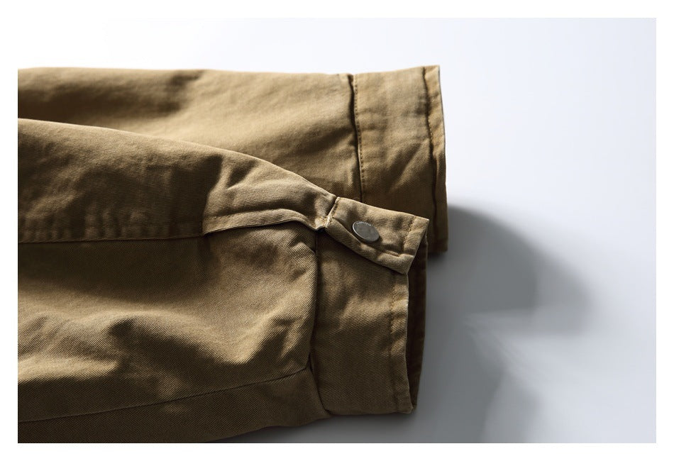Close-up of a tan-brown sleeve cuff with a buttoned fastening tab and stitched seams.