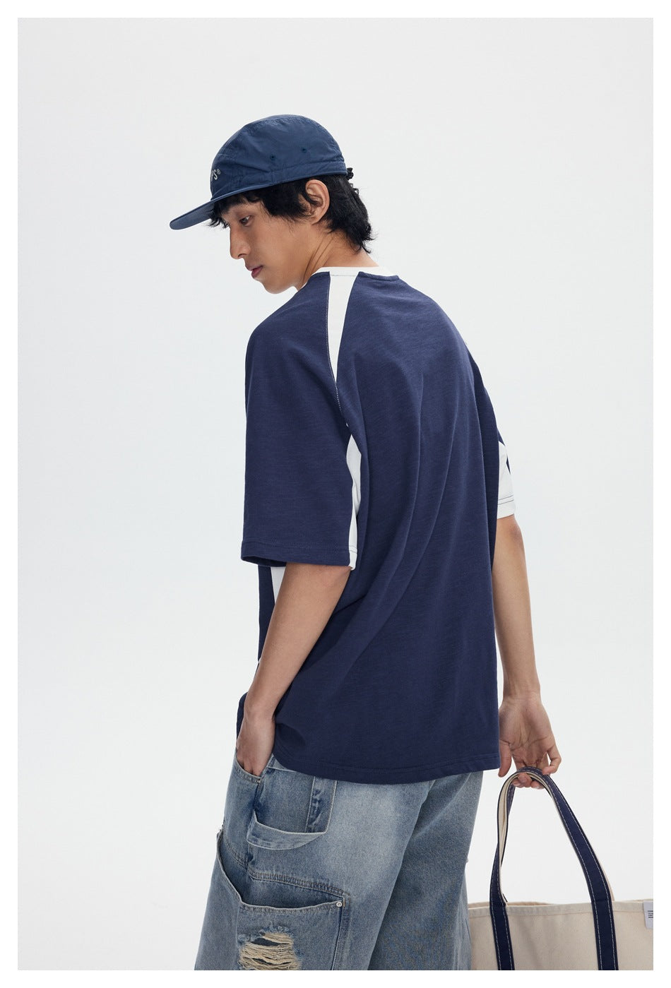Rear view of a model wearing a navy raglan T-shirt with white shoulder and sleeve accents.
