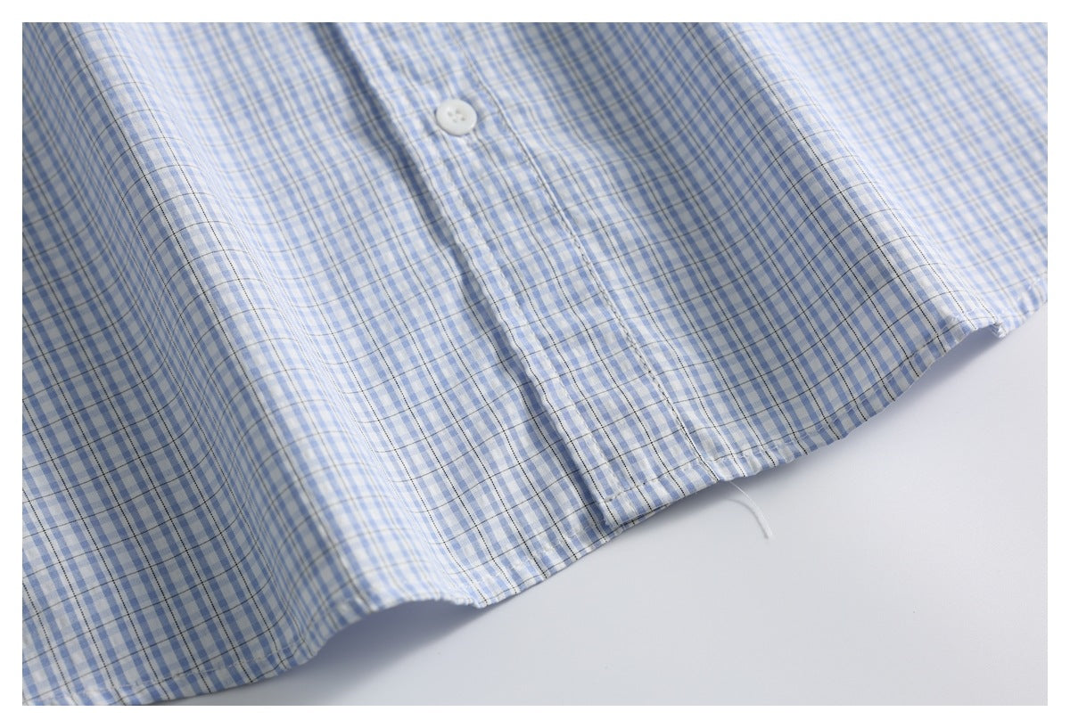 Close-up of the curved hem and button placket on a blue-and-white checked shirt.