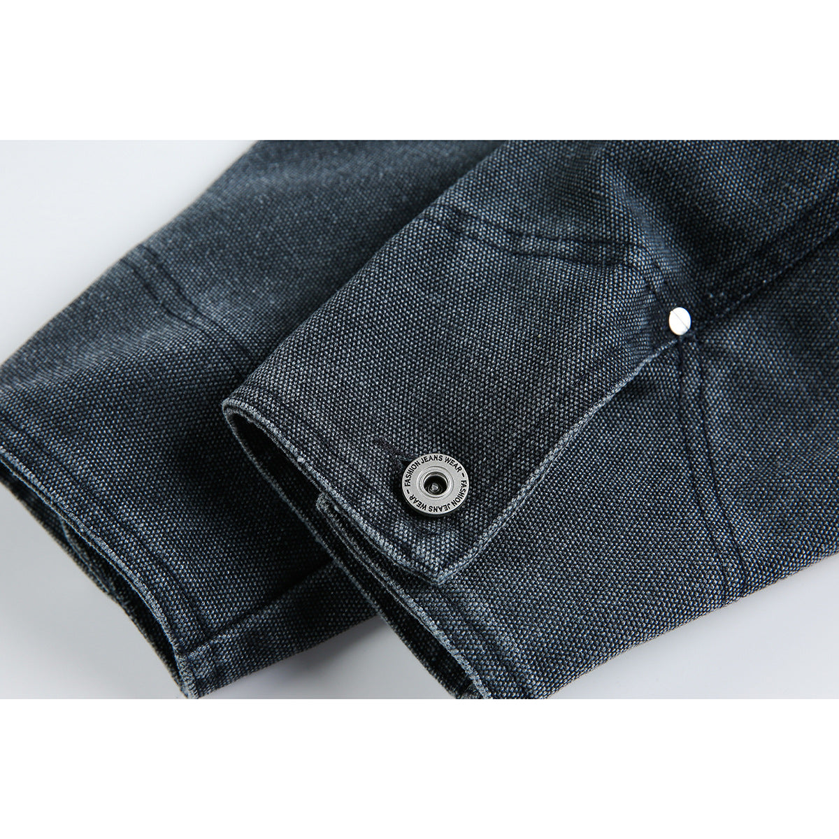 Close-up of a dark indigo jacket sleeve cuff with stitched seams and silver snap buttons.