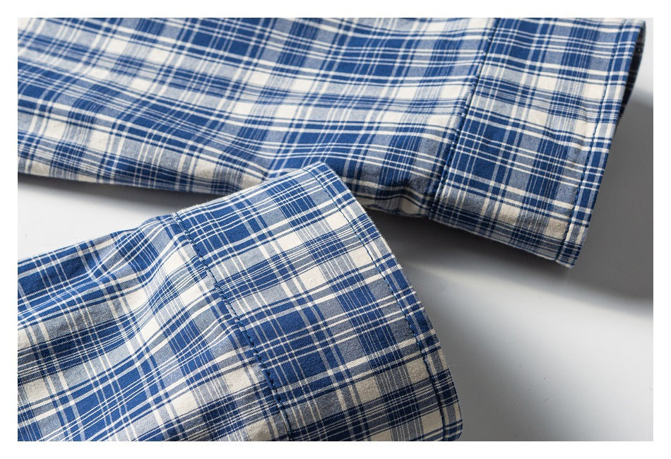 Close-up of blue, white, and gray plaid shirt fabric with two stitched cuffs visible.