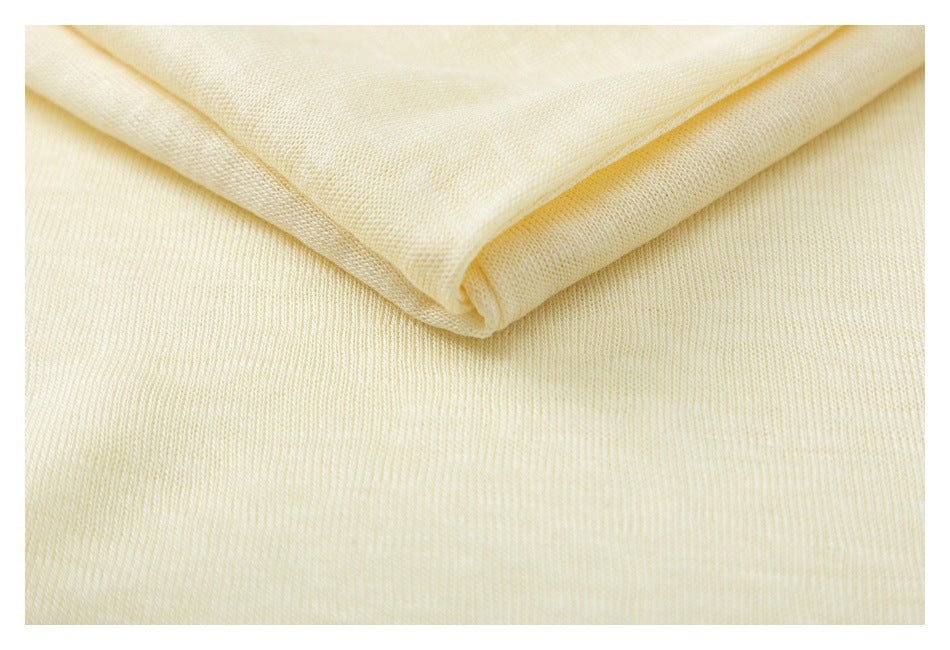 Close-up of pale yellow fabric folded over itself, showing its knit texture.