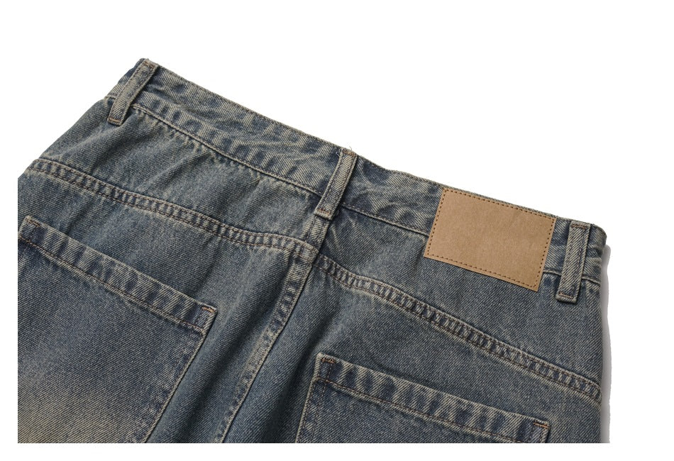 Close-up of the back waistband and pockets of faded blue jeans with a blank tan leather patch.