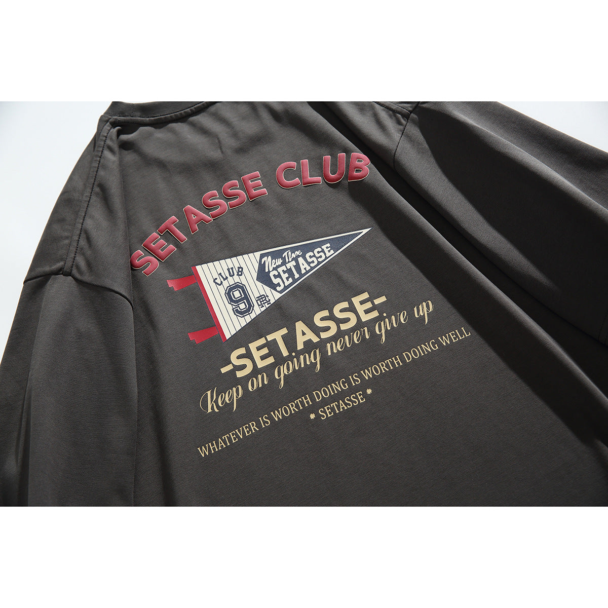 Close-up of a charcoal T-shirt back with large red, cream, and white text and pennant-style graphics.