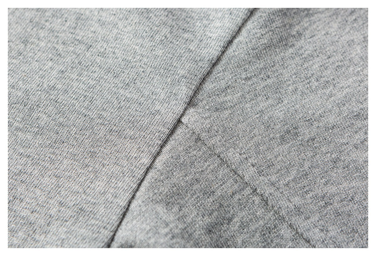 Extreme close-up of heather gray knit fabric showing its texture and a diagonal seam.