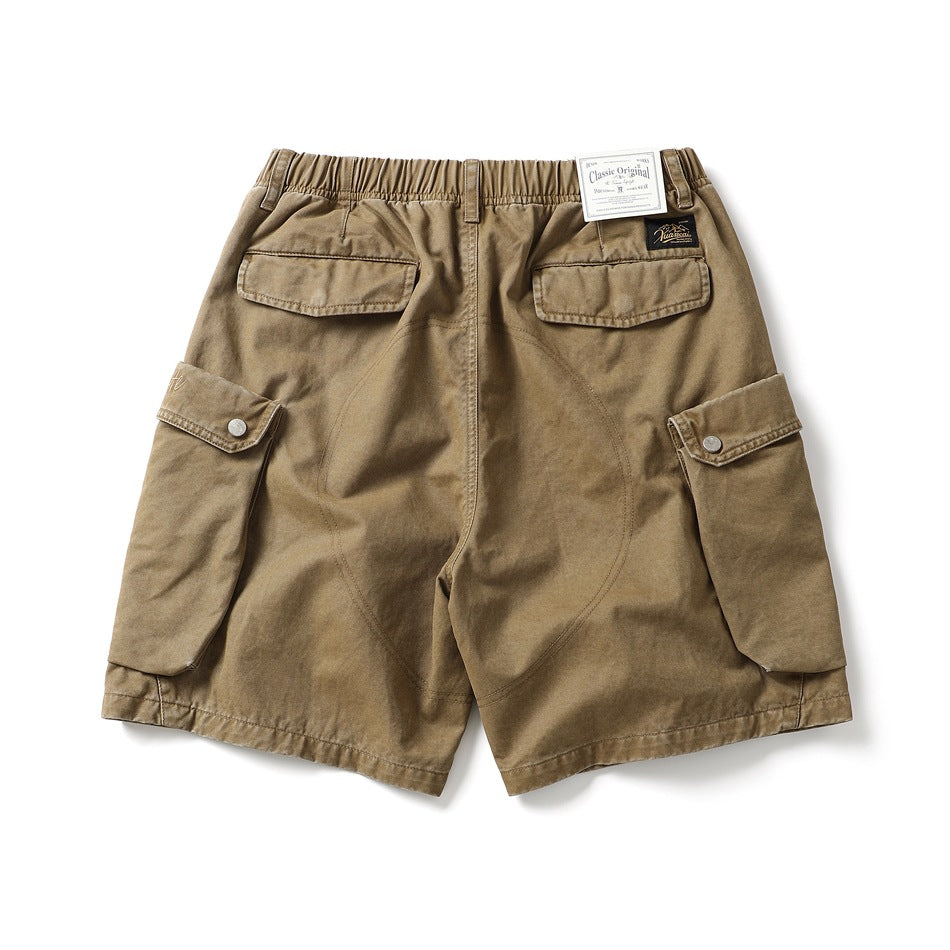 Back view of tan cargo shorts with an elastic waist, two flap pockets, and large snap-button side pockets.