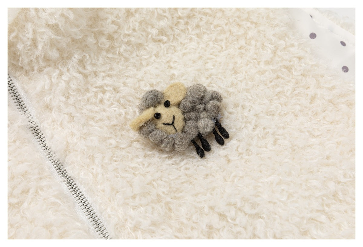 Close-up of a small sheep appliqué on cream curly pile beside a metal zipper and dotted lining.