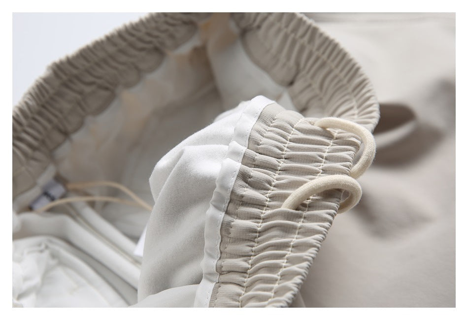 Inside view of light beige joggers showing the gathered waistband, drawstring channel, and pale lining.