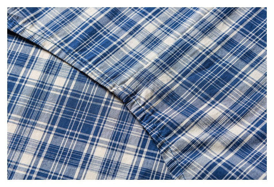 Close-up of blue, white, and gray plaid shirt fabric and a diagonal stitched seam.