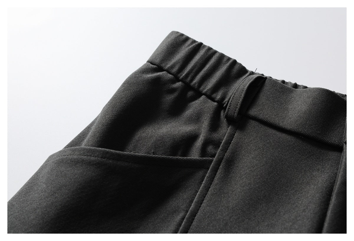 Close-up of dark trousers showing a gathered waist, belt loop and slanted side pocket.