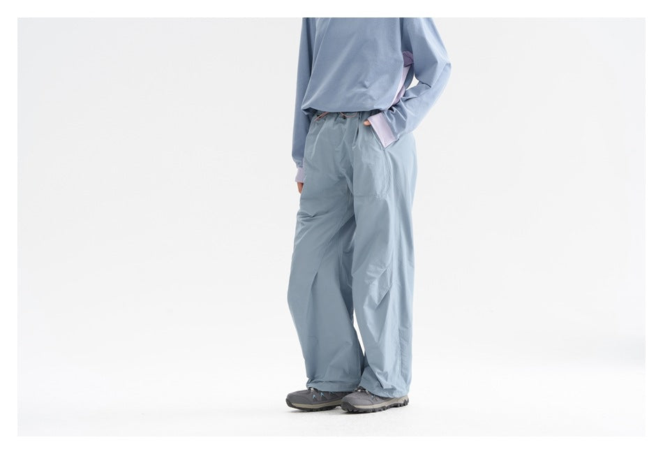 Angled view of a person wearing light blue wide-leg drawstring pants with a blue top.