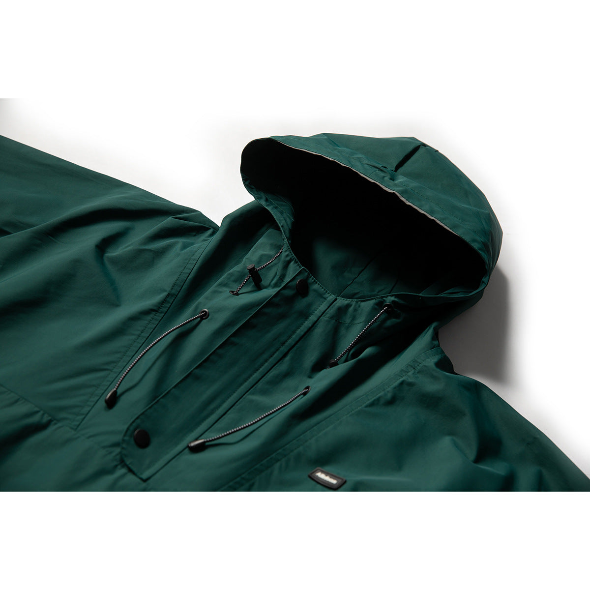 Close-up of a dark teal hooded pullover jacket showing its hood, drawcords, snap placket and chest patch.