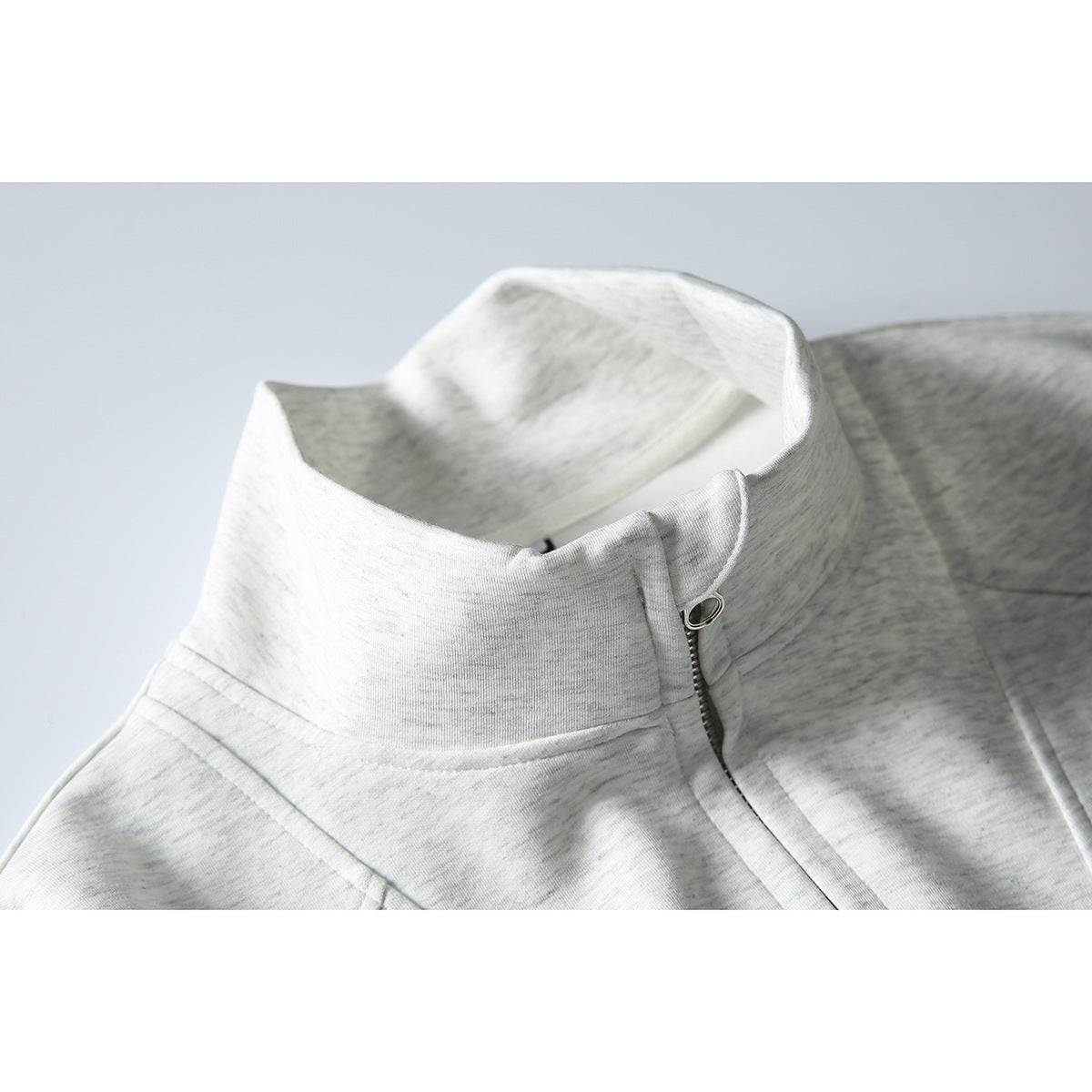 Close-up of a light gray heather quarter-zip sweatshirt collar and metal zipper pull.