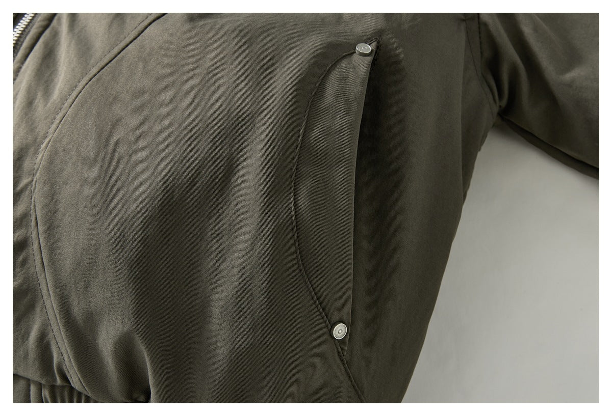Close-up of a dark olive jacket's curved snap-button pocket flap.
