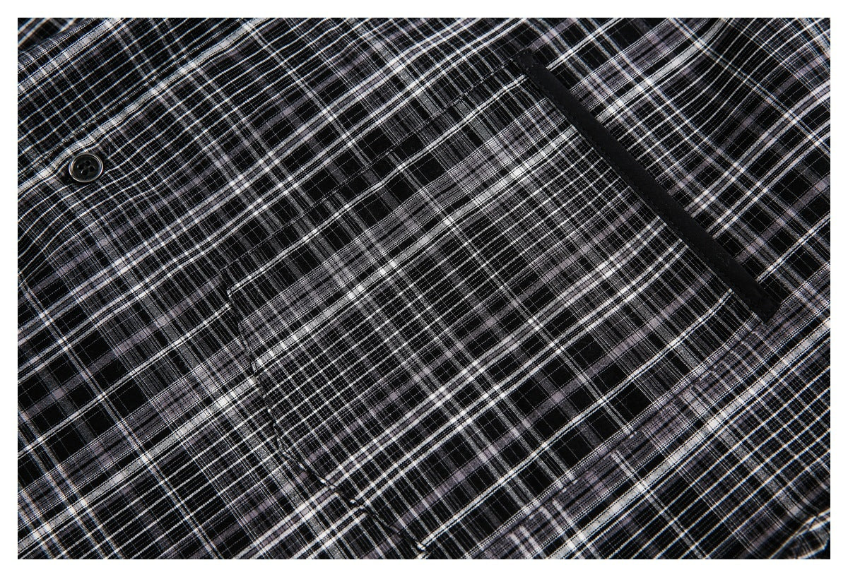 Close-up of black-and-gray plaid fabric showing a dark button and a black-trimmed pocket opening.