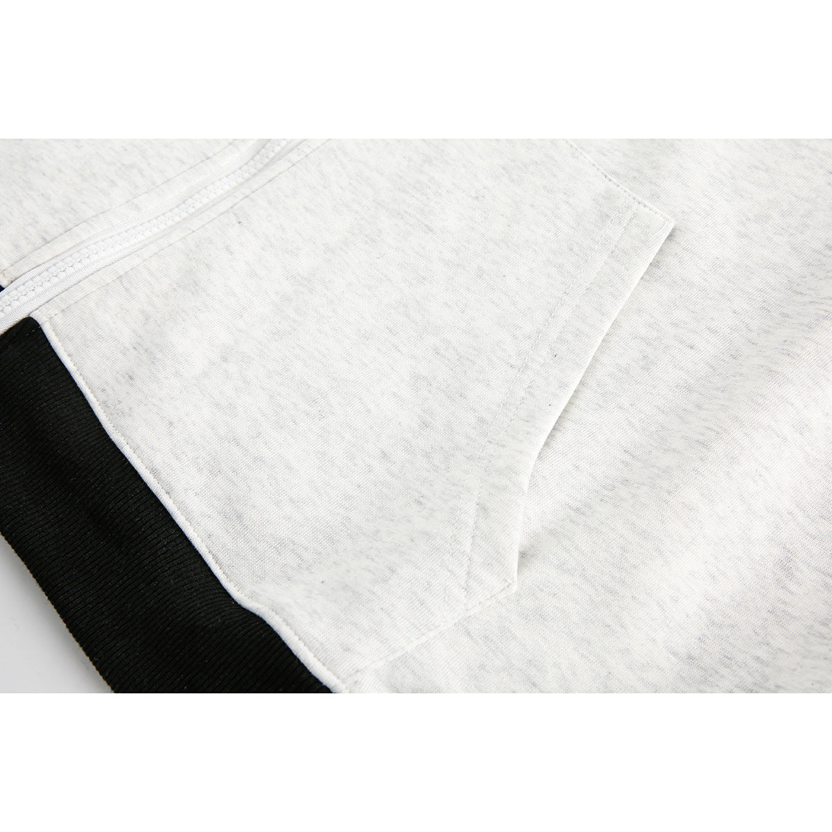 Close-up of a light gray hoodie pocket and black ribbed cuff.