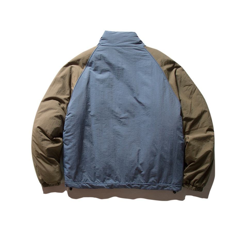 Back view of blue-gray padded jacket with olive-brown raglan sleeves, stand collar and elastic cuffs