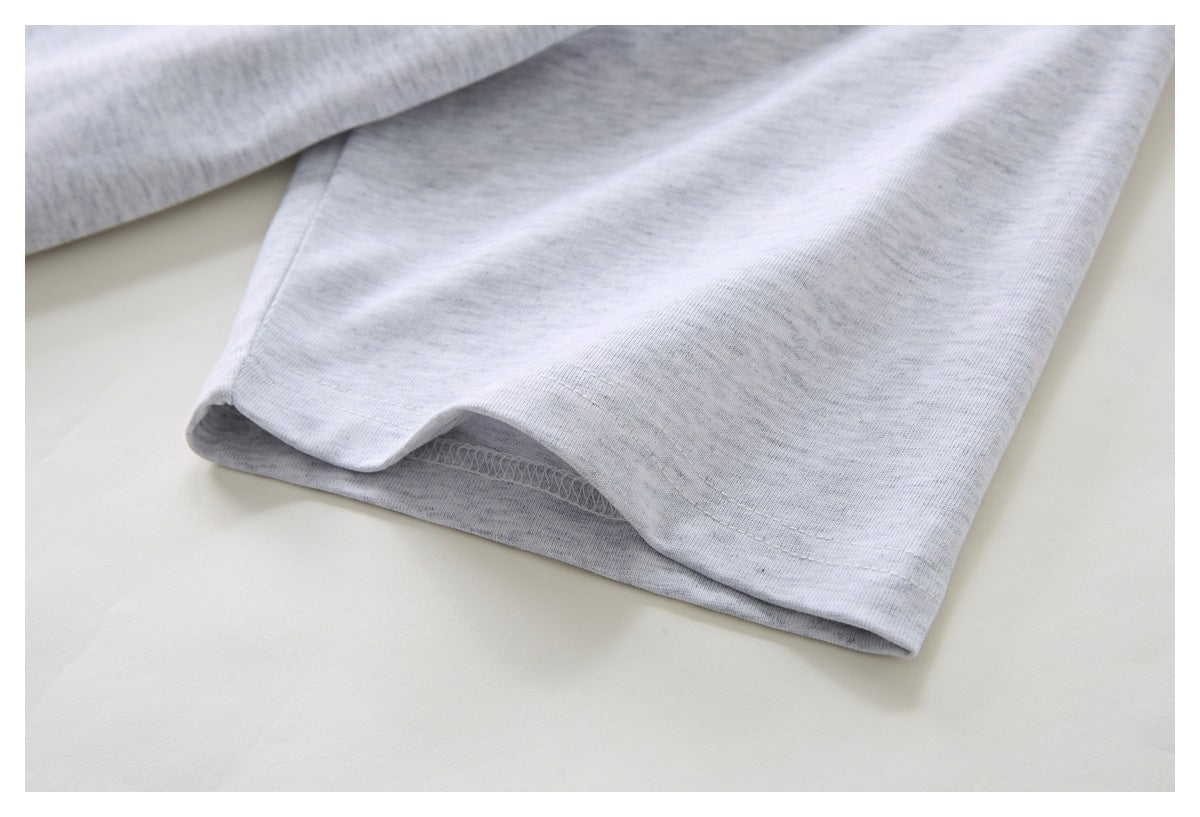 Close-up of the hem and stitched edge of a light gray T-shirt laid flat.