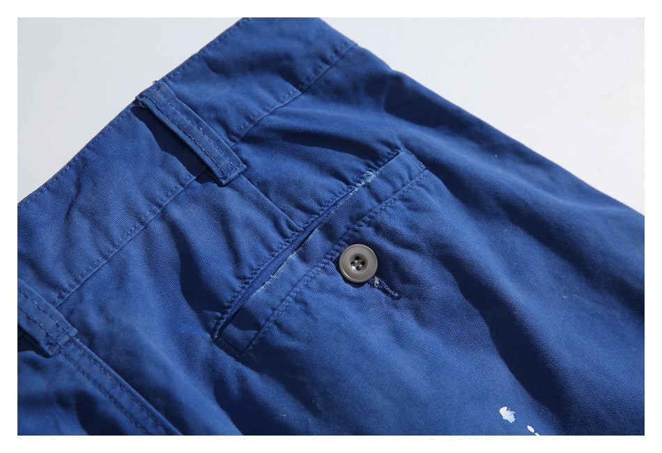 Close-up of a buttoned pocket and belt loop on royal-blue trousers, with small white marks near the edge.