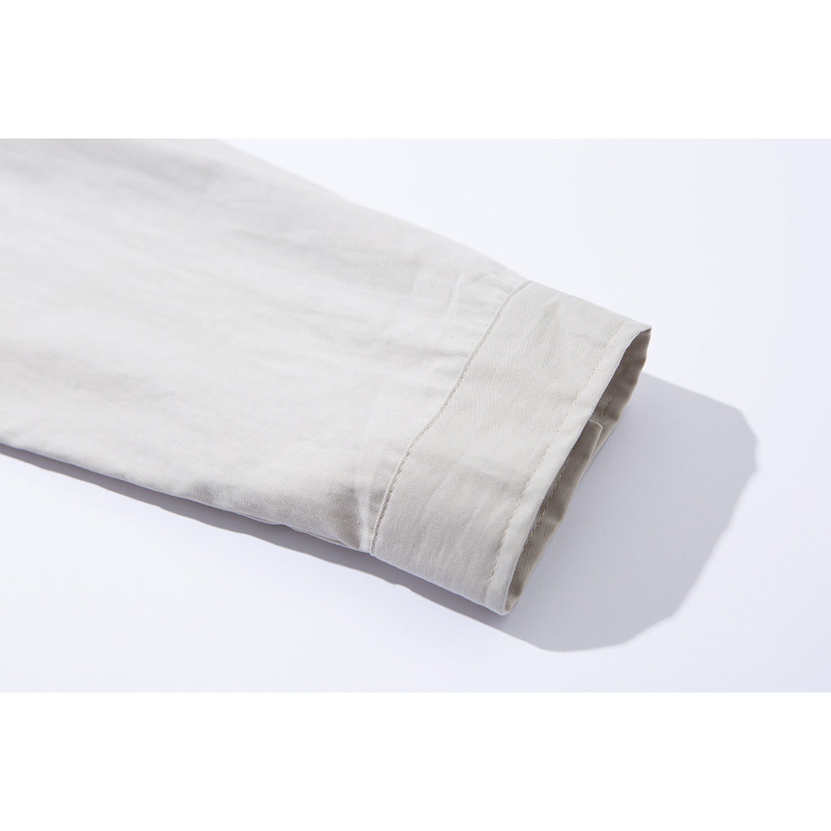 Close-up of a light gray shirt sleeve ending in a wide buttonless cuff.